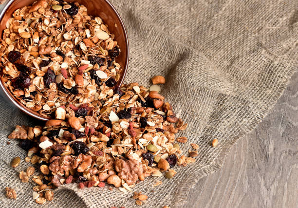 Homemade granola spilling from bowl on wooden table