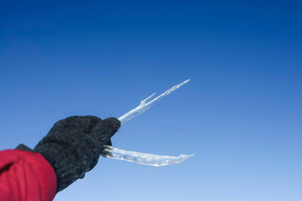 two big icicles in hand against a background of a spring blue sky