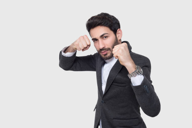 Portrait of serious businessman showing fist over gray background Portrait of serious businessman showing fist over gray background. Studio shot. Horizontal composition. punching one person shaking fist fist stock pictures, royalty-free photos & images