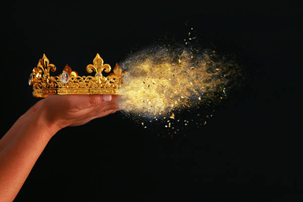 istock Woman's hand holding a crown for show victory or winning first place over black background. 930879580