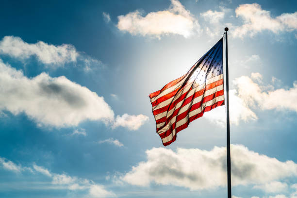 istock Blue Sky, Puffy Clouds, and American Flag waving into the Sunshine 930881210