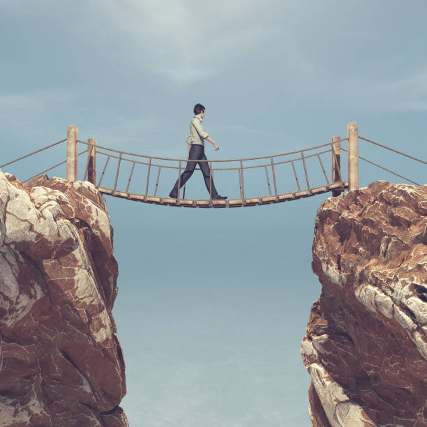 istock Man rope passing over a bridge suspended between mountains 930893084