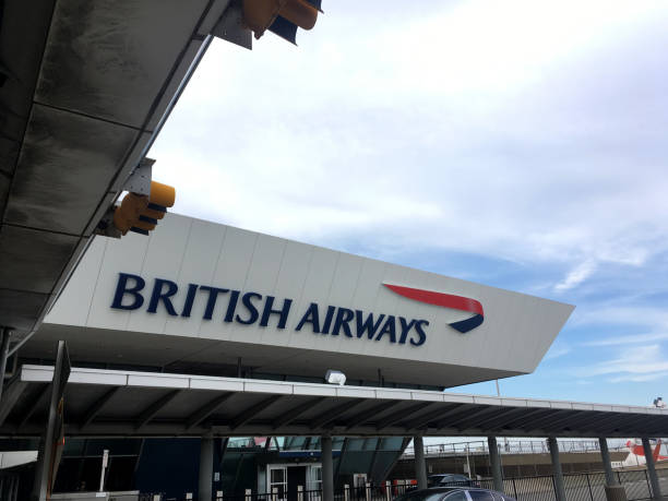 Entrance to the British Airways airline terminal at JFK airport in New York City. British Airways sign at the airport against clouds and blue skies. New York City - 10 August 2017: Entrance to the British Airways airline terminal at JFK airport in New York City. British Airways sign at the airport against clouds and blue skies. british airways stock pictures, royalty-free photos & images