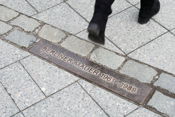 istock pedestrian walking across commemorative plaque for Berlin Wall 930896778