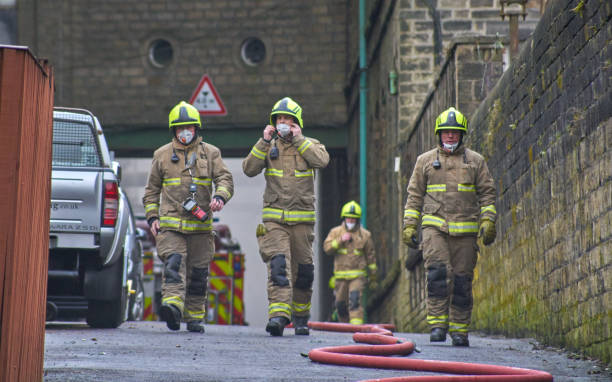 Firemen Recover from Smoke from Mill Building Fire stock photo