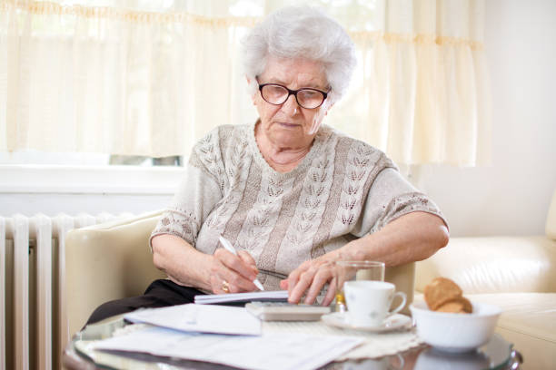 istock Old woman calculating bills at home. 930899332