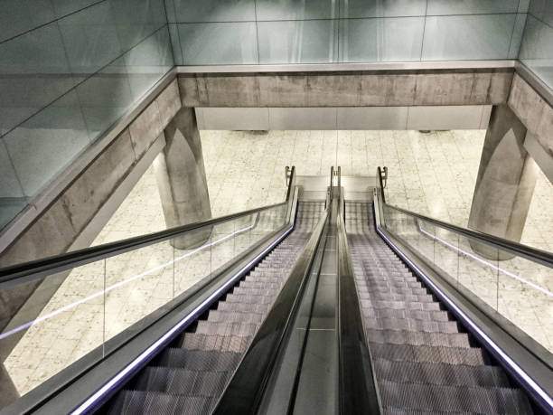 istock Looking down at Escalator with no people. Escalator going down to the next floor in a metro station. Clean, modern interior design at a transportation hub. Monochromatic Photo filter added. 930904568