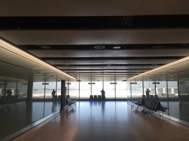 istock View looking down a long hallway at an airport backlit by windows of a man talking on his mobile phone at an airport in silhouette. Traveling for business, photo of an airport interior. 930904578