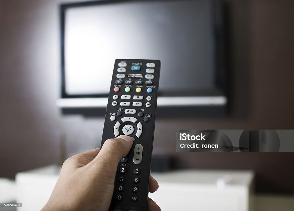 Television remote control with TV Hand holding TV remote control Broadcasting Stock Photo