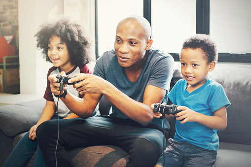 African American family at home sitting in sofa couch and playing console video games together.African American family at home sitting in sofa couch and playing console video games together