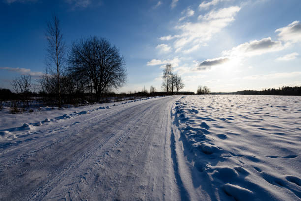 snowy winter road covered in deep snow with car tire tracks going in random directions