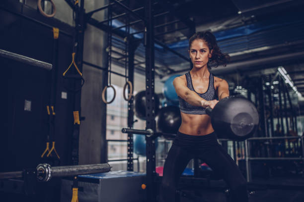 Pretty young woman exercising in gym Young beautiful woman exercising with kettlebell in the gym kettlebell stock pictures, royalty-free photos & images