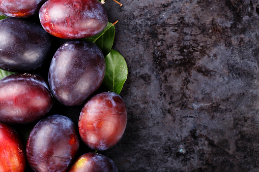 ripe plums scattered on a black background, space for text