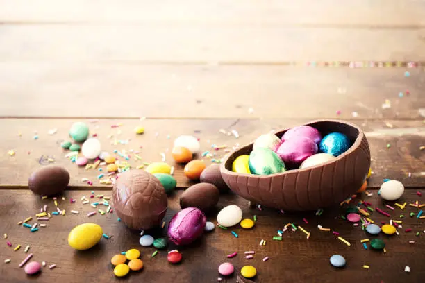 Photo of Chocolate easter eggs and sweet candies on wooden  background. Happy Easter!