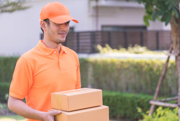 istock Delivery man in orange bringing in customer the package 930933552
