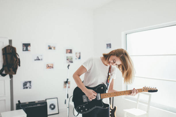 istock Young woman playing guitar in studio 930934276