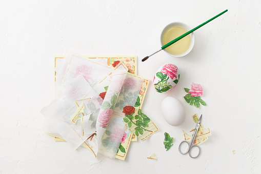 The process of creating decoupage on eggs in floral style. A delicate pink palette. Copy space text.