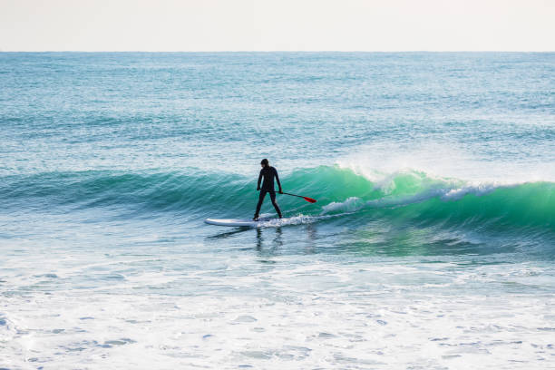 istock Surfer on stand up paddle board on ocean waves. Stand up paddle boarding in sea 930936632