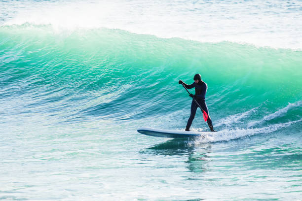 Surfer on sup board on ocean waves. Stand up paddle boarding in sea