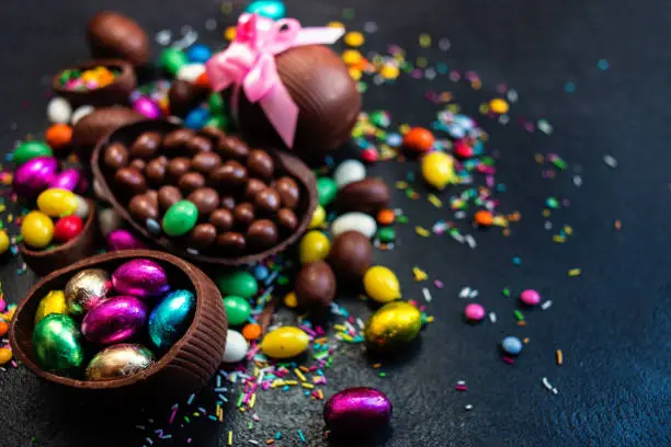 Photo of Chocolate easter eggs and sweet candies on dark stone background. Happy Easter!