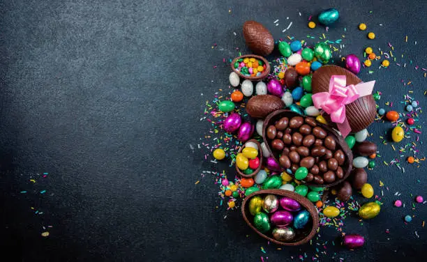 Photo of Chocolate easter eggs and sweet candies on dark stone background. Happy Easter!