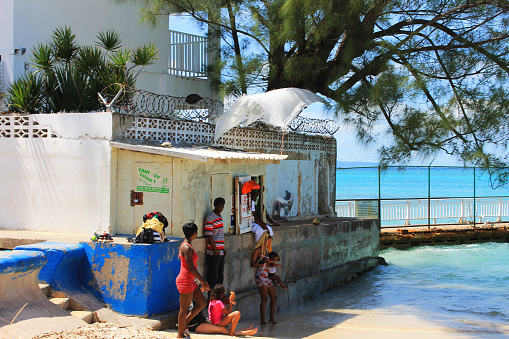 Local family on a small patch of roadside beach, Montego Bay, Jamaica. Partial building in picture.