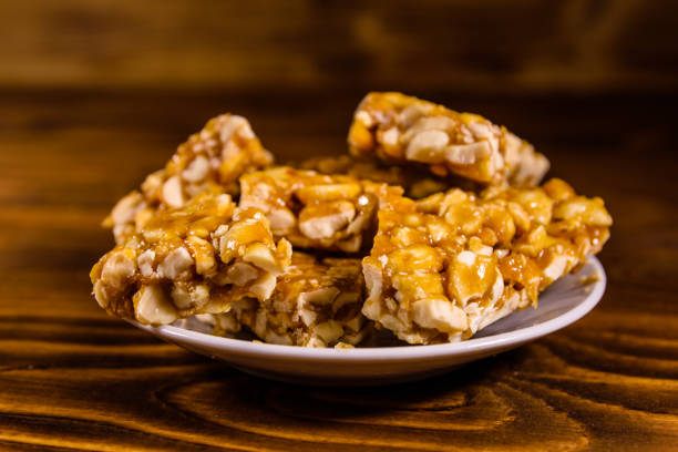 istock Ceramic plate with peanut brittles on wooden table. 930977814