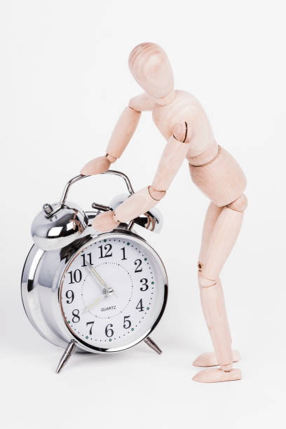 istock Wooden puppet is checking the alarm clock 930978836