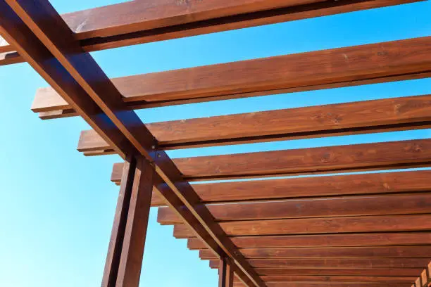 Part of the wooden roof structure on the gazebo on blue sky background.