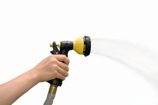 Young hand holding a spraying hose nozzle