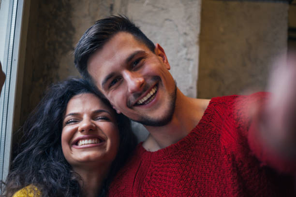 Young millennial couple taking selfie and making funny faces
