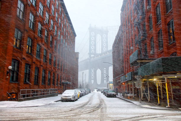 Winter in Brooklyn New York View down Pike Street toward the Manhattan Bridge during a snowstorm dumbo new york photos stock pictures, royalty-free photos & images