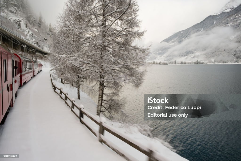 The Poschiavo lake seen from the Bernina Express train LE PRESE, SWITZERLAND - January, 2018. The Poschiavo lake seen from the Bernina Express train, Unesco world heritage, in winter with snow Alpine climate Stock Photo