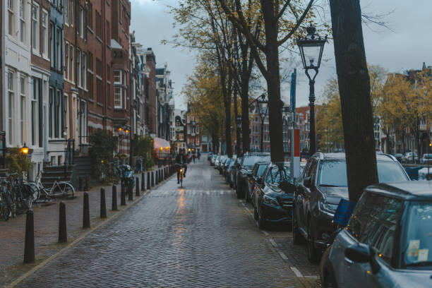 Street scene of canal coast with parked cars and bicycles at dusk time in Amsterdam Netherland