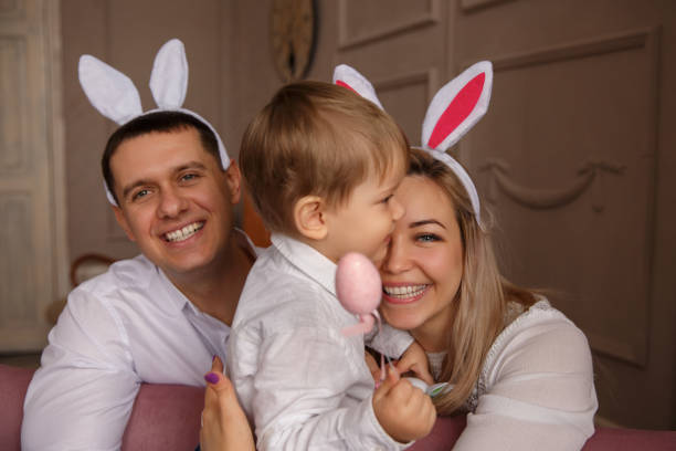 joyeuses pâques. jeune joyeuse famille avec enfant célébrant le jour de pâques. mère et père portant des oreilles de lapin de pâques dimanche - easter rabbit bizarre women photos et images de collection