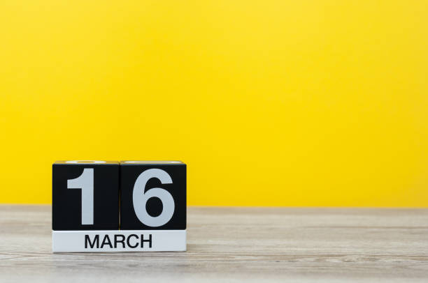 istock March 16th. Day 16 of month, calendar on table with yellow background. Spring day, empty space for text 931025608