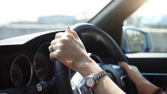 Closeup of beautiful woman hands holding a car steering wheel confidently.