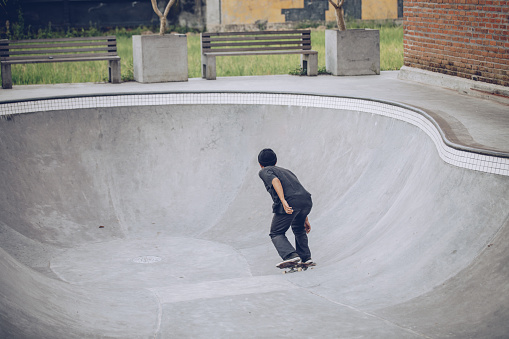 One man, riding skateboard alone in skate park, rear view.