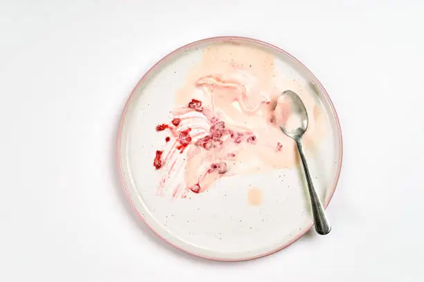 Top view of empty and dirty plate after raspberry ice cream has been eating