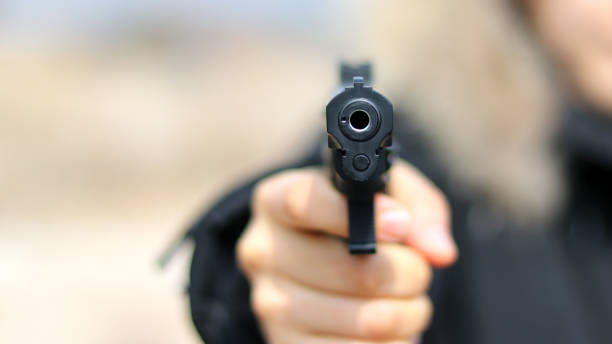 Woman pointing a gun at the target on soft background. stock photo