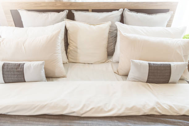 Bed maid-up with clean white pillows and bed sheets in beauty room. Close-up. Lens flair in sunlight. Bed maid-up with clean white pillows and bed sheets in beauty room. Close-up. Lens flair in sunlight. sailboat mast stock pictures, royalty-free photos & images
