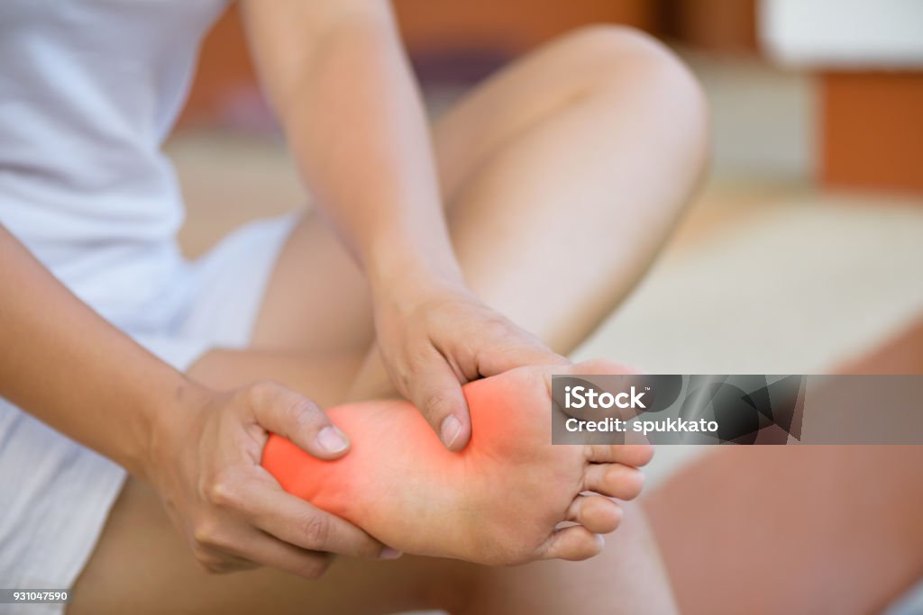 Closeup young woman feeling pain in her foot at home. Healthcare and medical concept. Human Foot Stock Photo