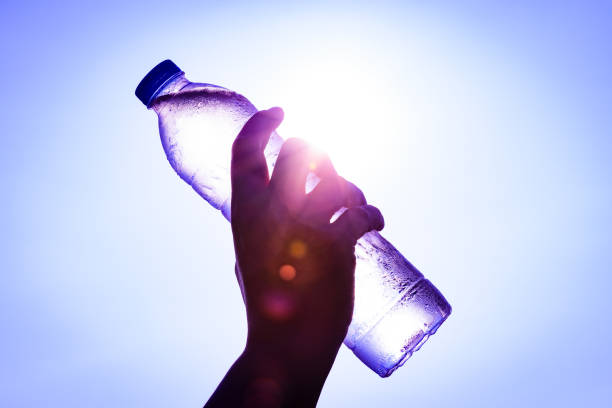 istock Silhouette of closeup Woman's hand holding plastic water bottle over sunlight effect. World Water Day concept. 931048234