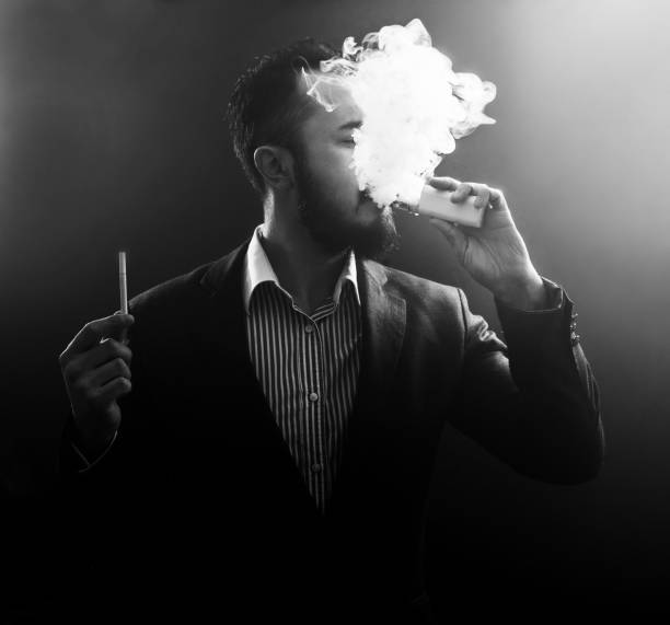 istock vaping man holding a mod and cigarette. A cloud of vapor. 931051316