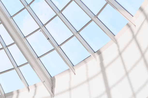Modern builduing interior. Glass ceiling or steel structure in shopping mall. Blue sky on background. Glass roof, view fron inside. Transparent hall
