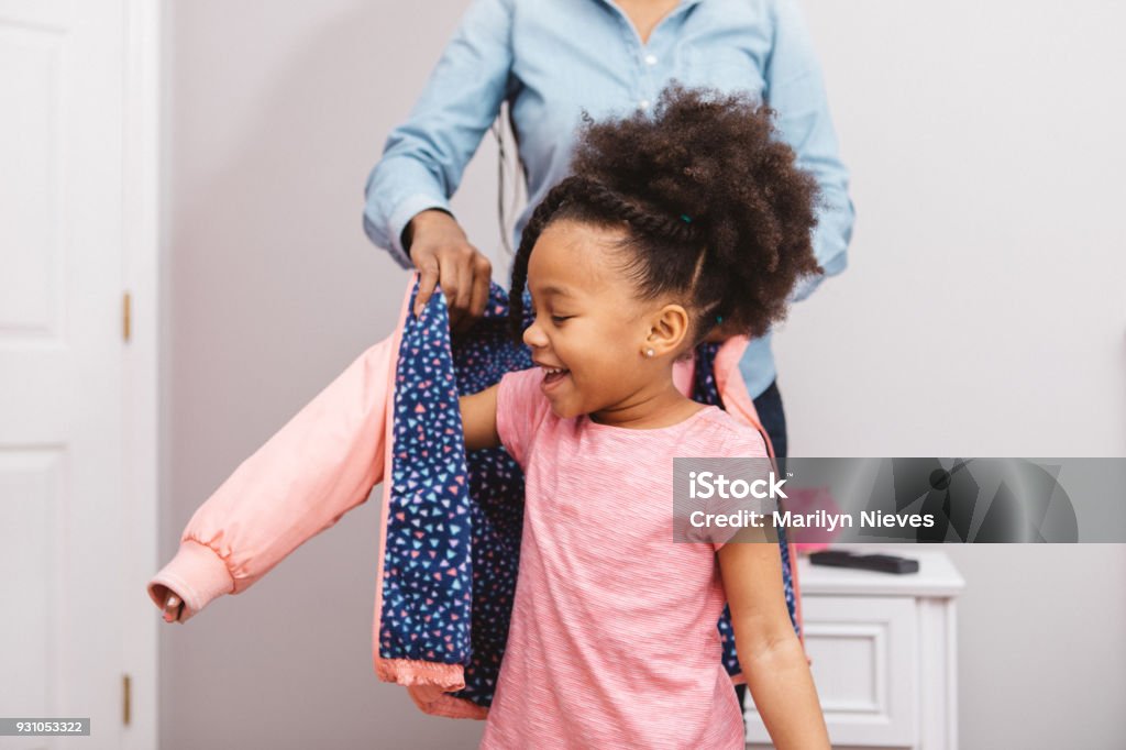 little girl getting ready for school Little girl putting on her jacket to head out. Child Stock Photo