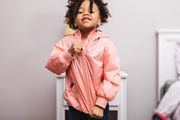 little girl getting ready for school Little girl putting on her jacket to head out. getting dressed photos stock pictures, royalty-free photos & images