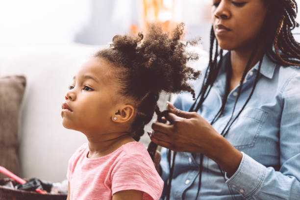 mother styling daugher's hair Little girl getting her hair twisted by her mom. braided hair stock pictures, royalty-free photos & images