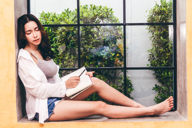 istock Woman with pen writing on a notebook sitting at home 931069414