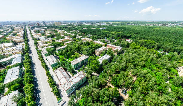 Aerial city view with crossroads and roads, houses, buildings, parks and parking lots. Sunny summer panoramic image - fotografia de stock